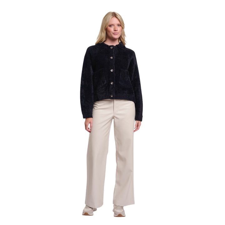 Woman wearing a black jacket and beige pants on a white background