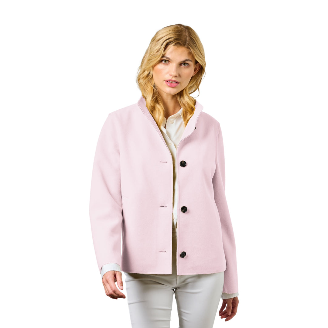 Woman wearing a light pink jacket with black buttons on a white background