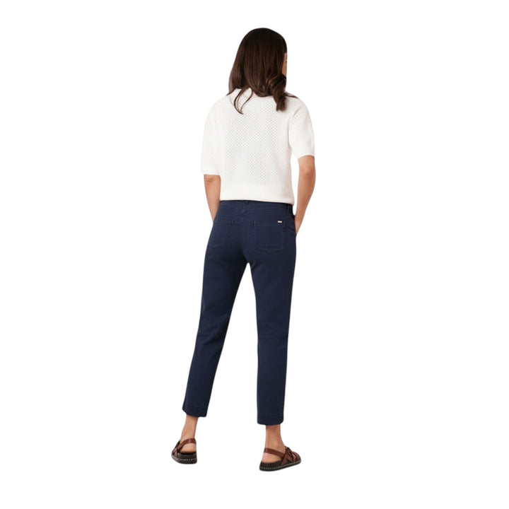 Woman wearing navy pants and a white top on a white background